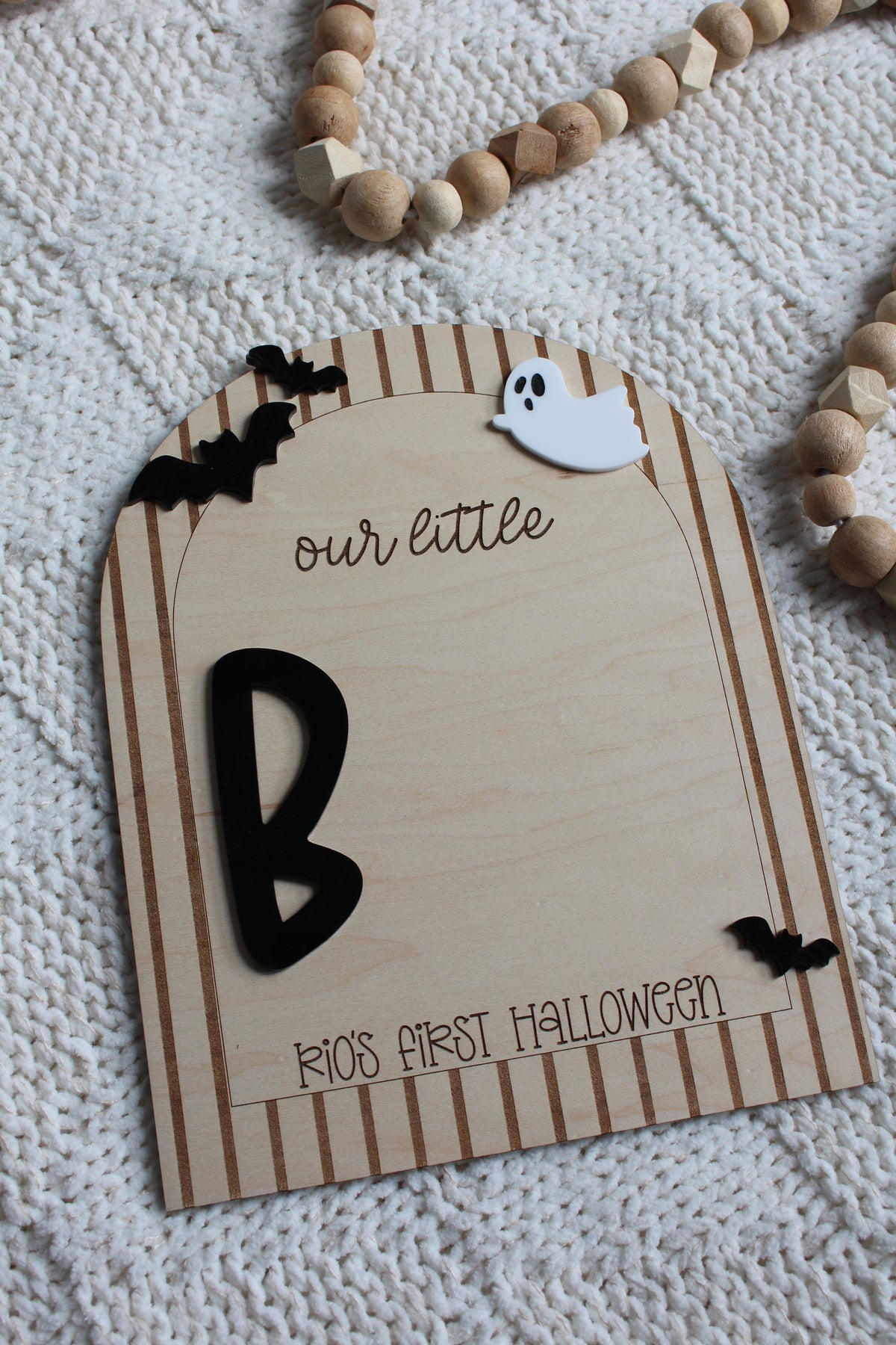 Personalized wooden Baby's First Halloween footprint board with striped arch border, black bats, white ghost and blank space for baby's painted footprints.