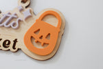 Close-up of orange jack-o’-lantern bucket detail on a personalized wooden Halloween Boo Basket tag