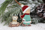 Personalized wooden Christmas ornament featuring a child in vintage winter clothing pulling a teddy bear on a sled, customized with the name Wyatt and year 2026