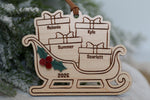 Personalized family Christmas ornament 2026 featuring a wooden Santa sleigh filled with engraved name presents, layered holly berries, and a brown hanging ribbon.