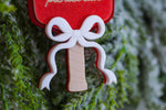 Close-up of a red glitter pickleball paddle Christmas ornament with a layered white bow and engraved wooden handle.