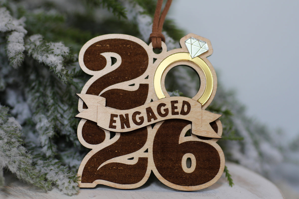 First Christmas engaged ornament featuring wooden 2026 numbers, a gold engagement ring, and Engaged banner, a Christmas gift for newly engaged couples
