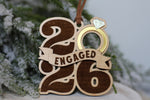 First Christmas engaged ornament featuring wooden 2026 numbers, a gold engagement ring, and Engaged banner, a Christmas gift for newly engaged couples