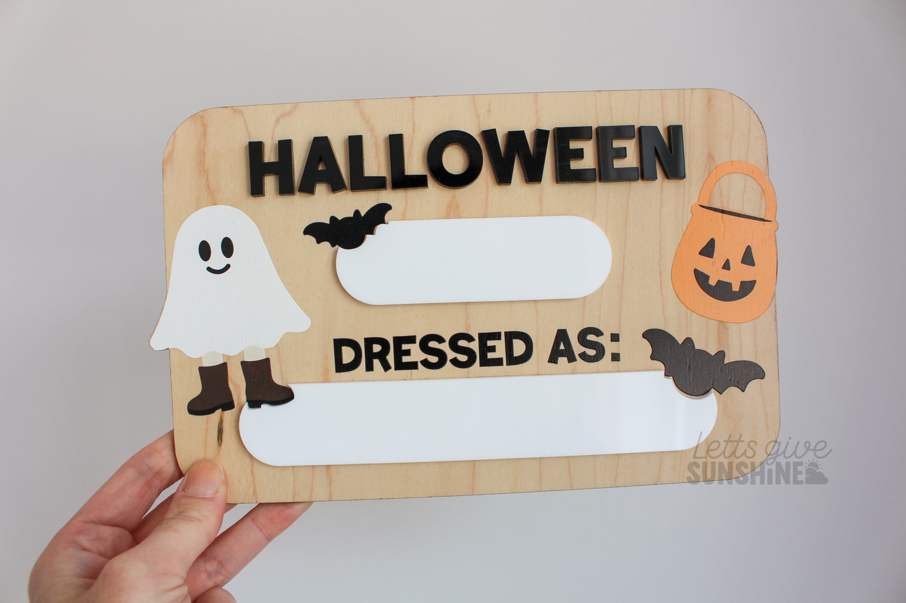 Reusable wooden Halloween photo prop board with dry erase spaces for the year and child’s costume, decorated with ghost, bats, and pumpkin bucket