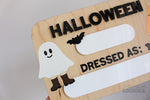 Reusable wooden Halloween photo prop board with dry erase spaces for the year and child’s costume, decorated with ghost, bats, and pumpkin bucket