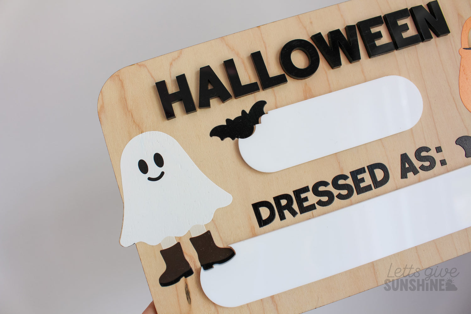 Reusable wooden Halloween photo prop board with dry erase spaces for the year and child’s costume, decorated with ghost, bats, and pumpkin bucket