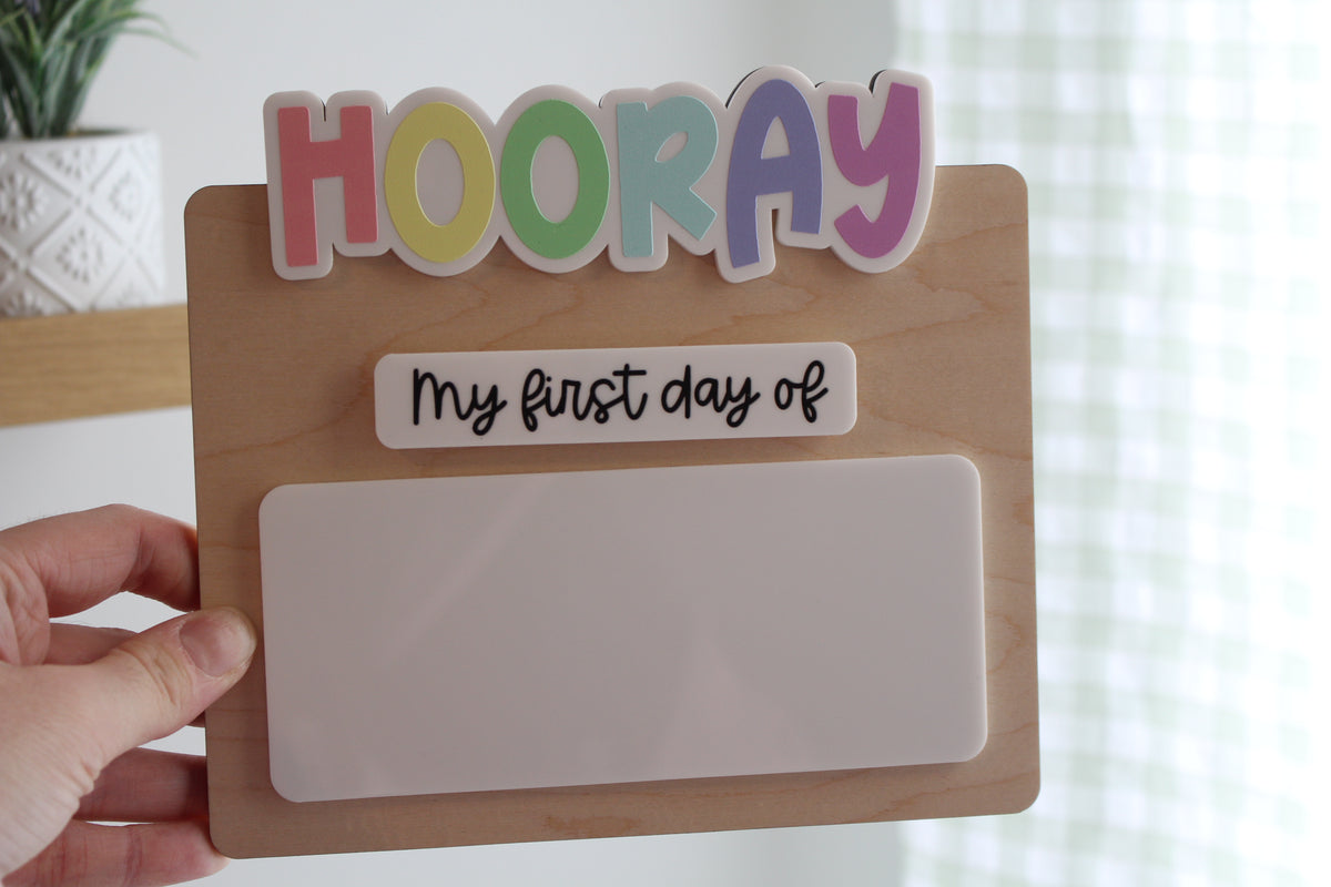Wooden first day of school photo prop with colourful HOORAY lettering and blank dry erase area for school details.