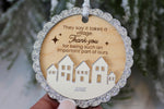 Daycare provider Christmas thank you gift featuring a wooden It Takes a Village ornament with engraved message, silver ribbon and decorative village design