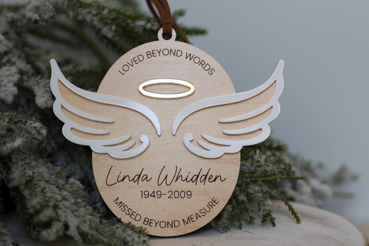 In loving memory Christmas ornament made from layered wood and acrylic with white angel wings, halo, engraved memorial quote, and personalized name and dates
