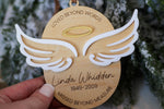 Personalized bereavement ornament with angel wings and halo, featuring the name Linda Whidden, memorial years, and a decorative wood oval shape