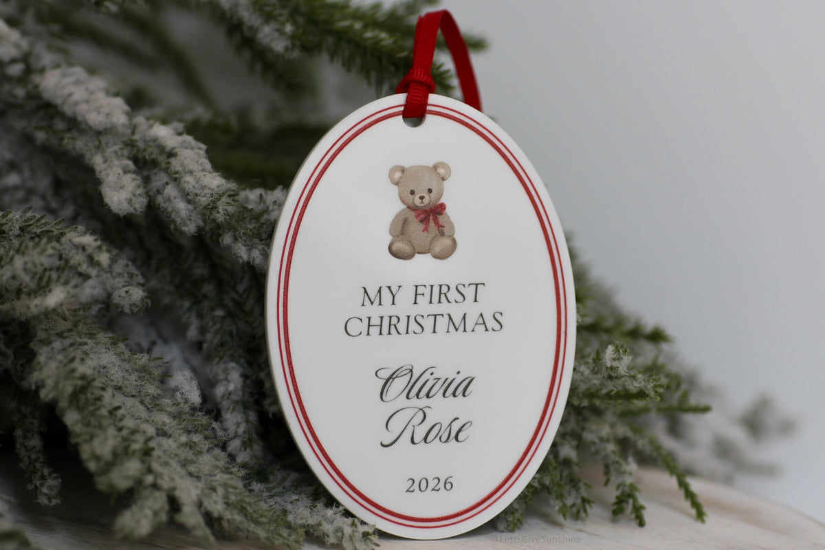 Personalized Baby's First Christmas 2026 ornament featuring a vintage teddy bear, Olivia Rose's name, red border and velvet ribbon on white acrylic.