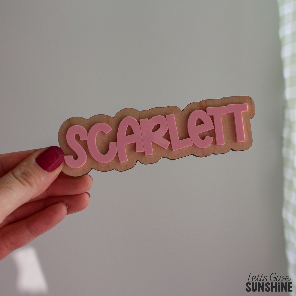 Close-up of a personalized wooden name piece reading “Scarlett” in raised pink acrylic lettering, designed to attach to a reusable first day of school milestone board.