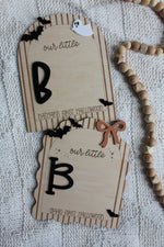 Personalized wooden Baby's First Halloween footprint board with striped arch border, black bats, white ghost and blank space for baby's painted footprints.