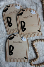 Personalized wooden Baby's First Halloween footprint board with striped arch border, black bats, white ghost and blank space for baby's painted footprints.