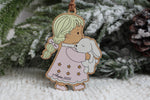 Personalized wooden Christmas ornament featuring a little girl with blonde braids wearing a pink star-patterned nightgown and holding a white bunny, with the name Amelia and year 2026.