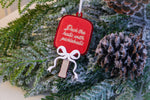 Red glitter pickleball paddle Christmas ornament with a layered white bow and the words Deck the halls with pickleballs.