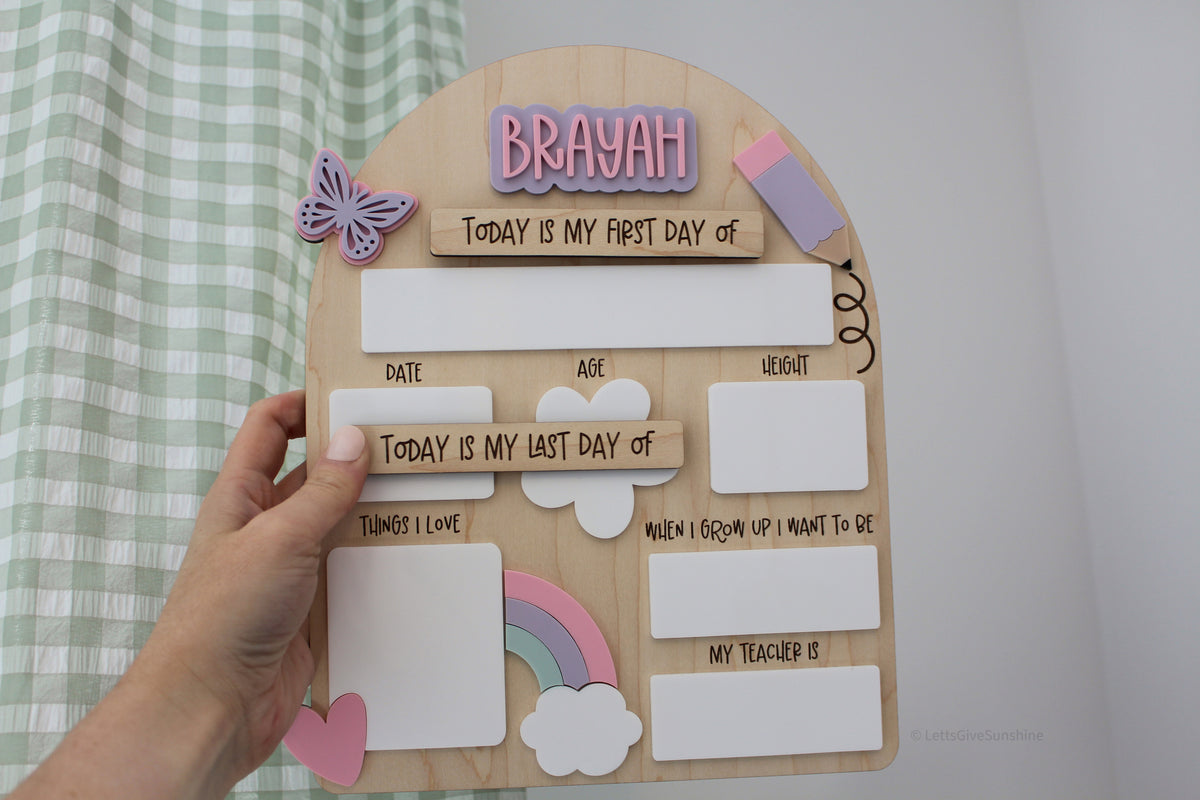 Personalized wooden first and last day of school board with a pink and purple name, pastel rainbow, butterfly, hearts, and reusable dry-erase spaces