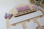Close-up of a personalized first day of school board with the name Brayah, an interchangeable wooden first day sign, and a white dry-erase space for the grade