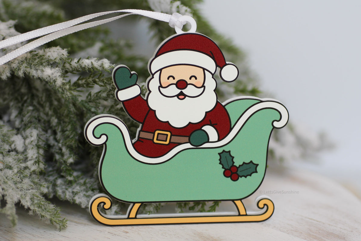 Santa Tracker Christmas ornament featuring Santa waving from a green Christmas sleigh, made from acrylic with a white hanging ribbon.