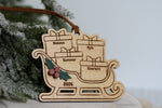 Personalized family Christmas ornament 2026 featuring a wooden Santa sleigh filled with engraved name presents, layered holly berries, and a brown hanging ribbon.
