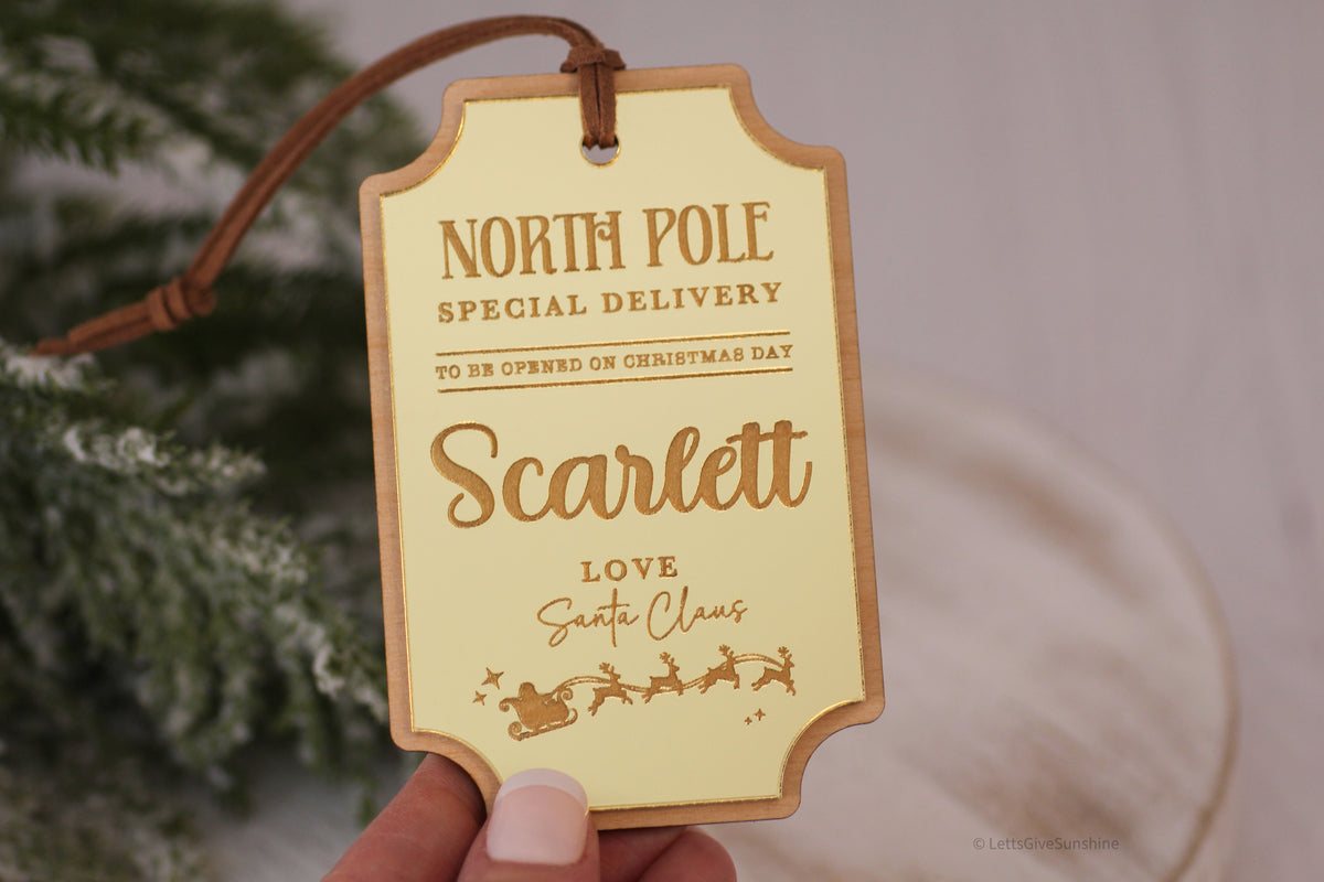 Reusable personalized Christmas gift tag featuring a vintage North Pole Special Delivery design, gold acrylic finish and Santa Claus signature.