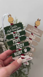 Personalized family Christmas ornament 2026 featuring green and neutral colour options, custom family name signs, optional pet paw prints, and Santa Stop Here wooden design